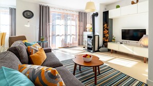 A modern living room with a sofa, a TV, a fireplace, and a dining area. - Apartamenty Sun & Snow Komuny Paryskiej (Karpacz)