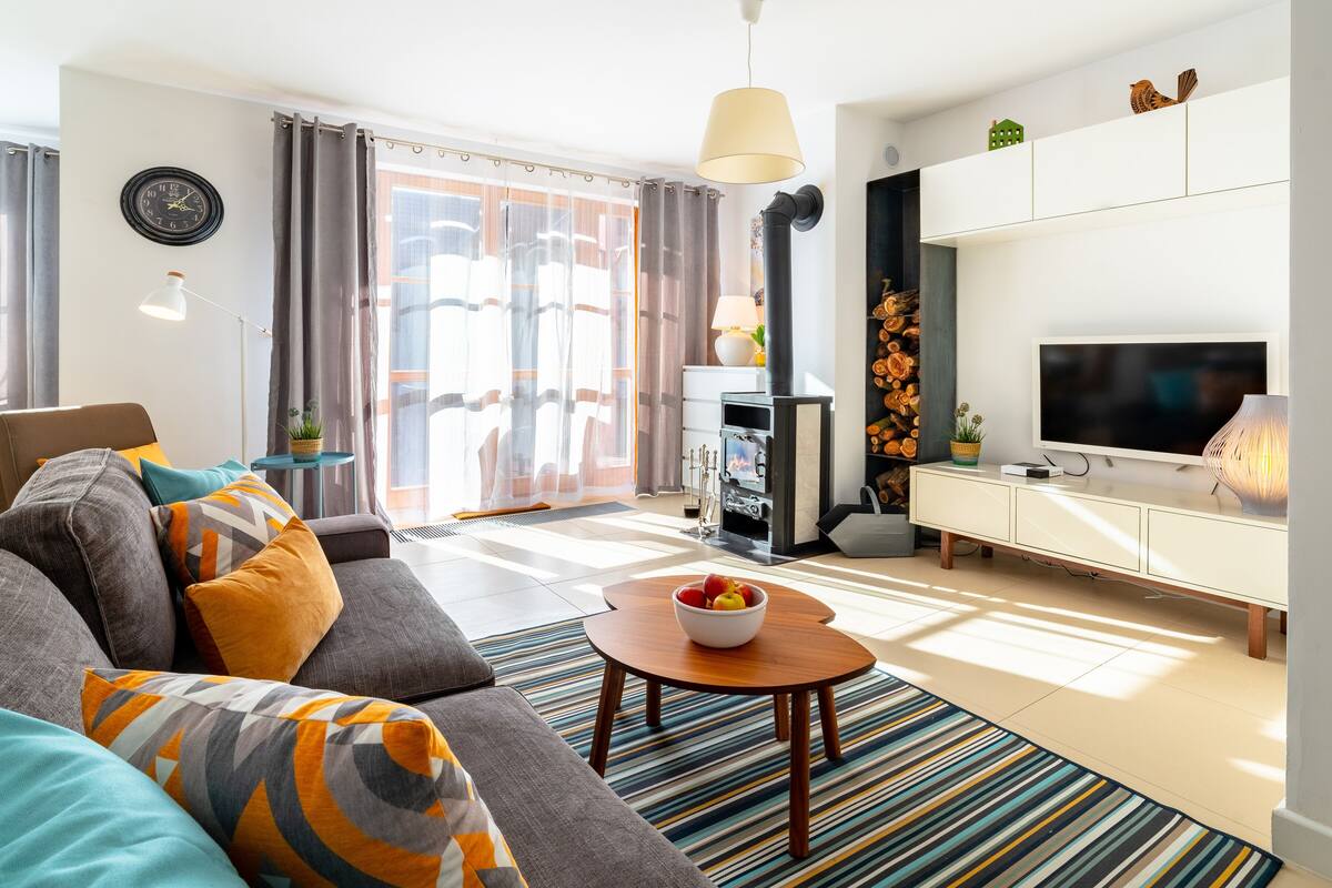 Ein modernes Wohnzimmer mit einer Couch, einem Fernseher, einem Kamin und einem Essbereich.