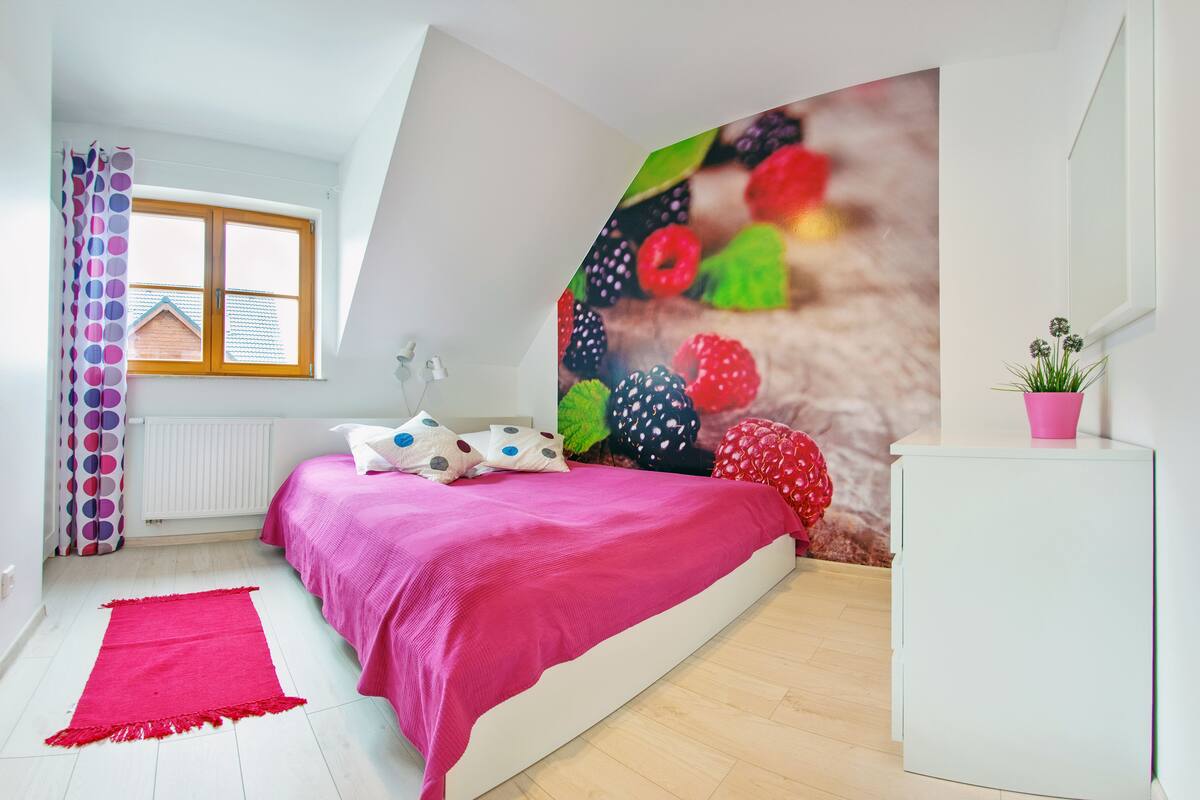 Ein Schlafzimmer mit Bett, Schminktisch, Fenster und Wandgemälde.