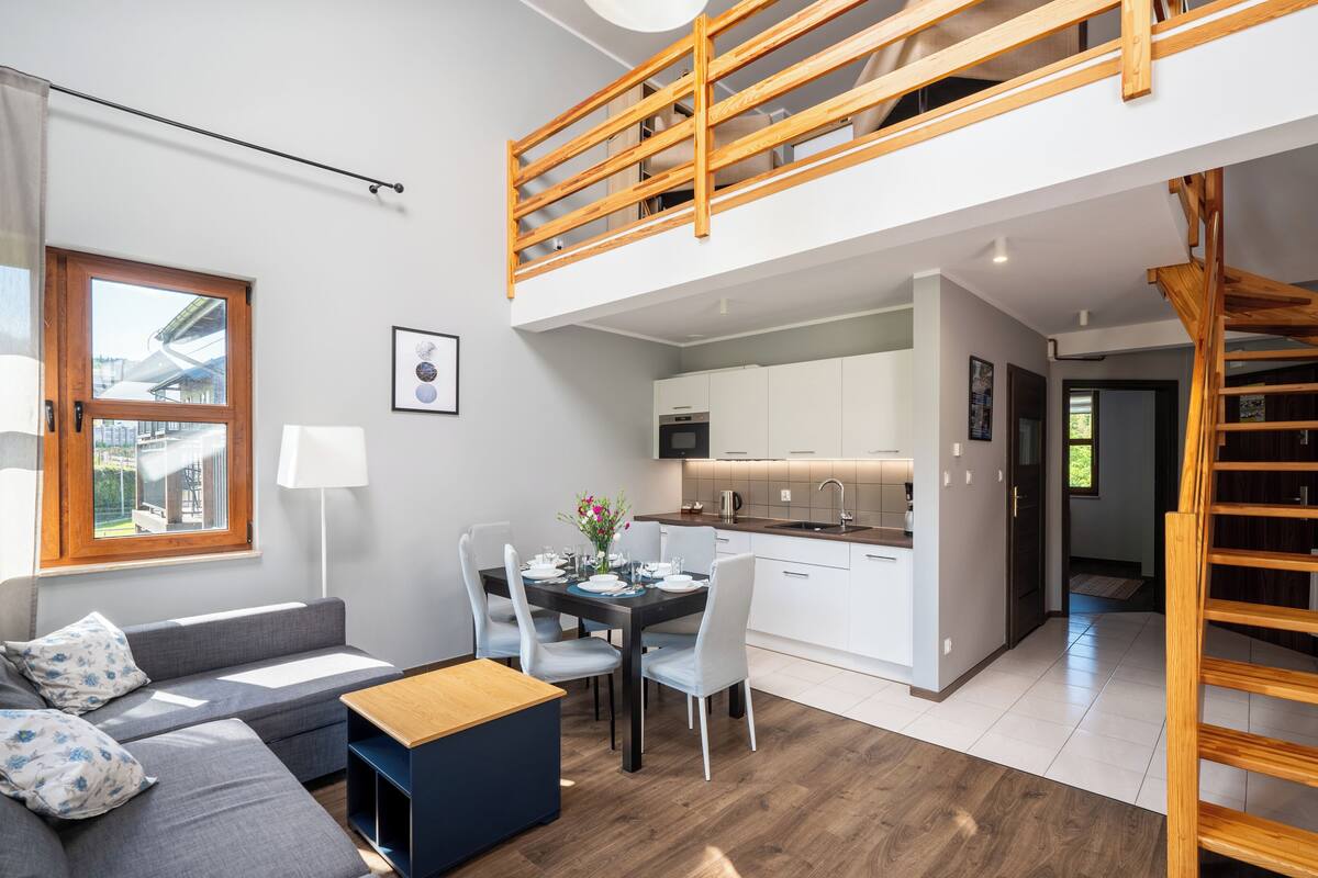Een modern appartement met een slaapkamer op entresol, een eethoek en een keuken.