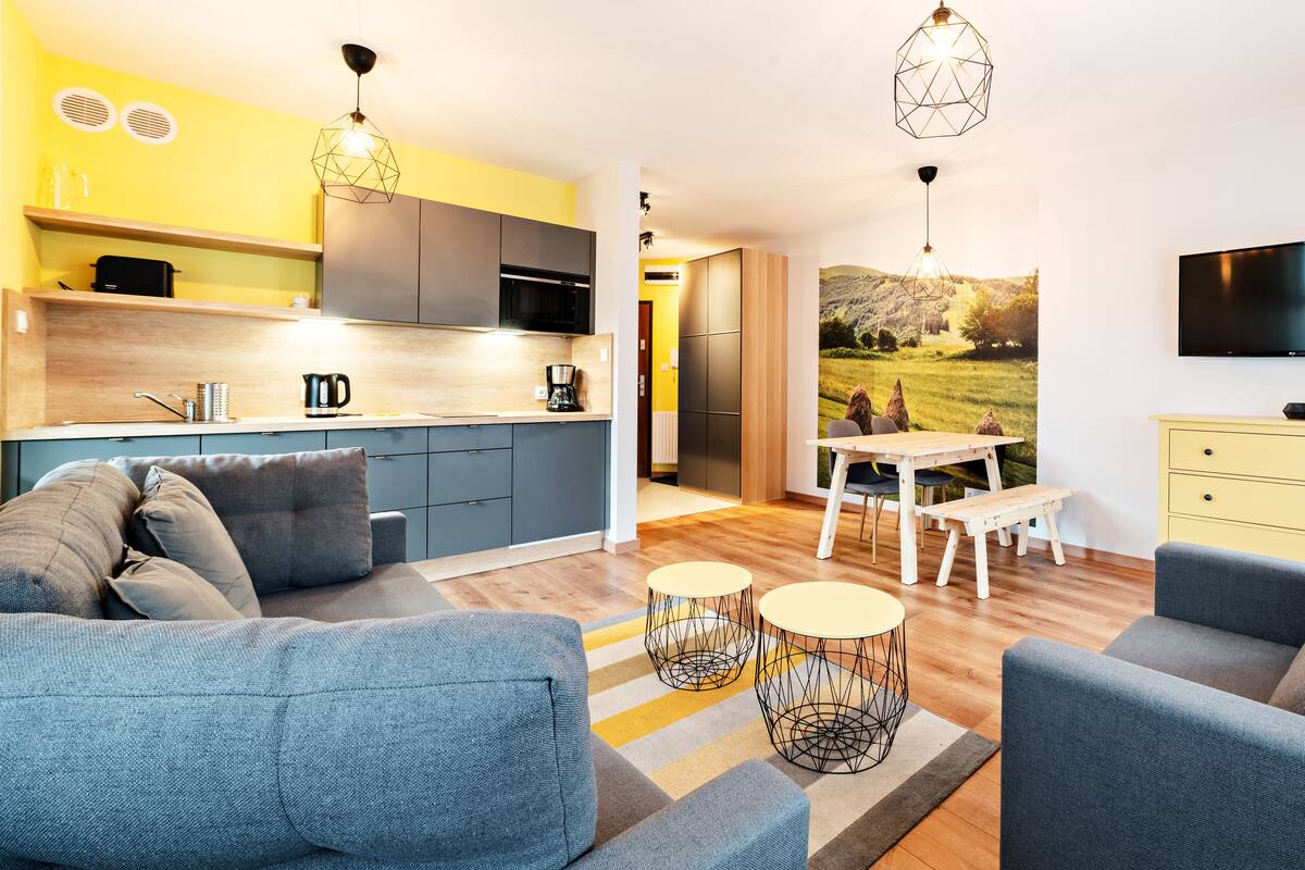 Een moderne woonkamer met een bank, salontafel en een eethoek met een tafel en stoelen.