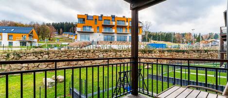 Un balcón con pared de piedra, terraza de madera y vista a edificios modernos.