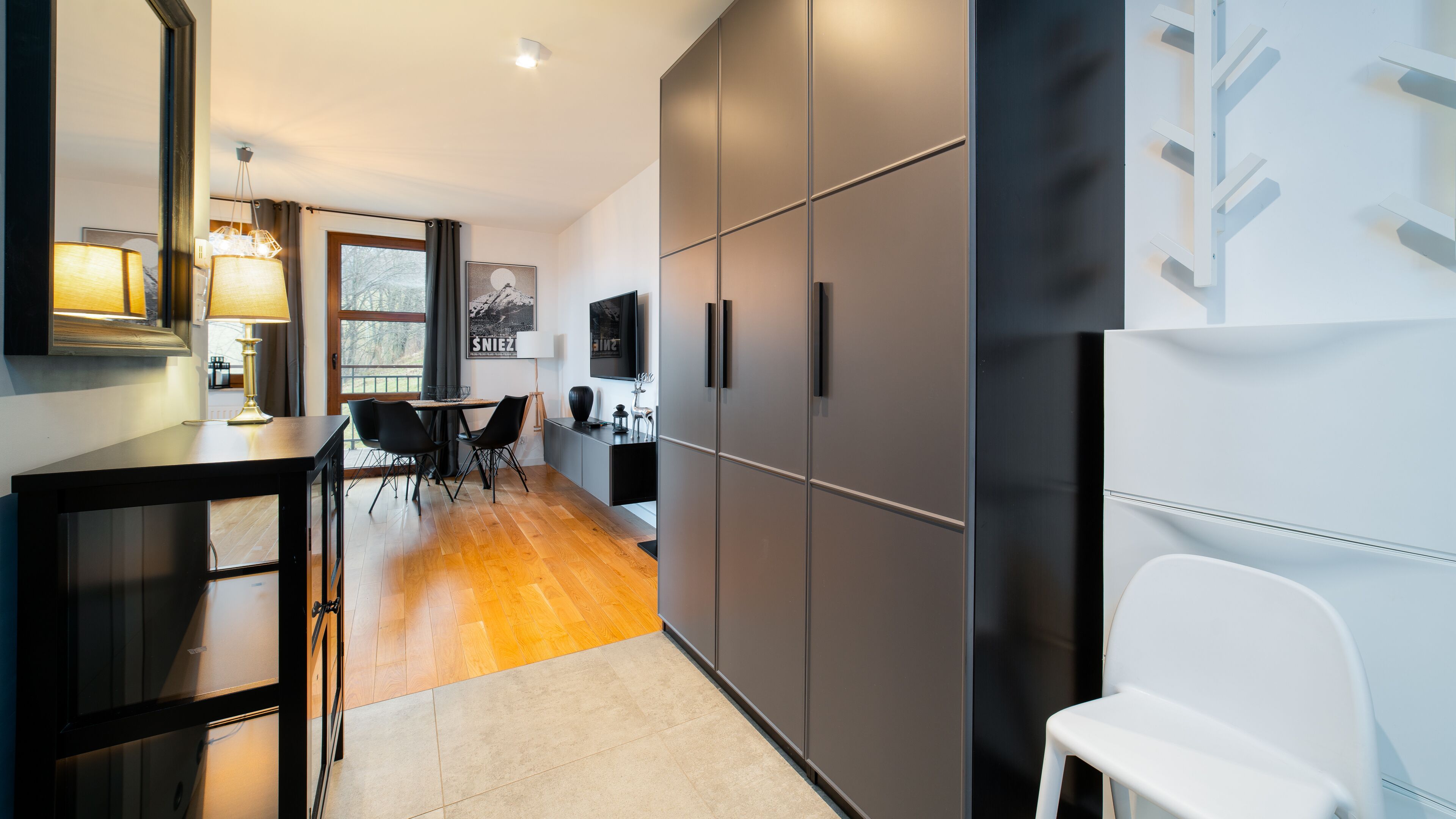 A modern kitchen with a dining area, wooden flooring, and a large cabinet.