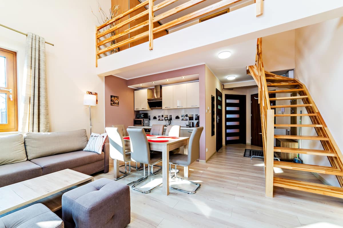 Een modern appartement met een slaapkamer op entresol, een eethoek en een keuken.