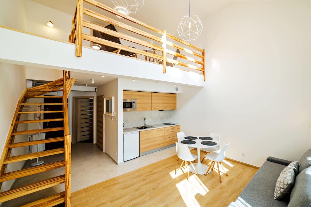 Een modern loft appartement met keuken, eethoek en een trap naar een slaaploft.