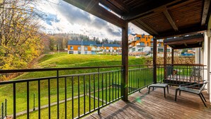 A wooden deck with a view of modern buildings and a grassy area.