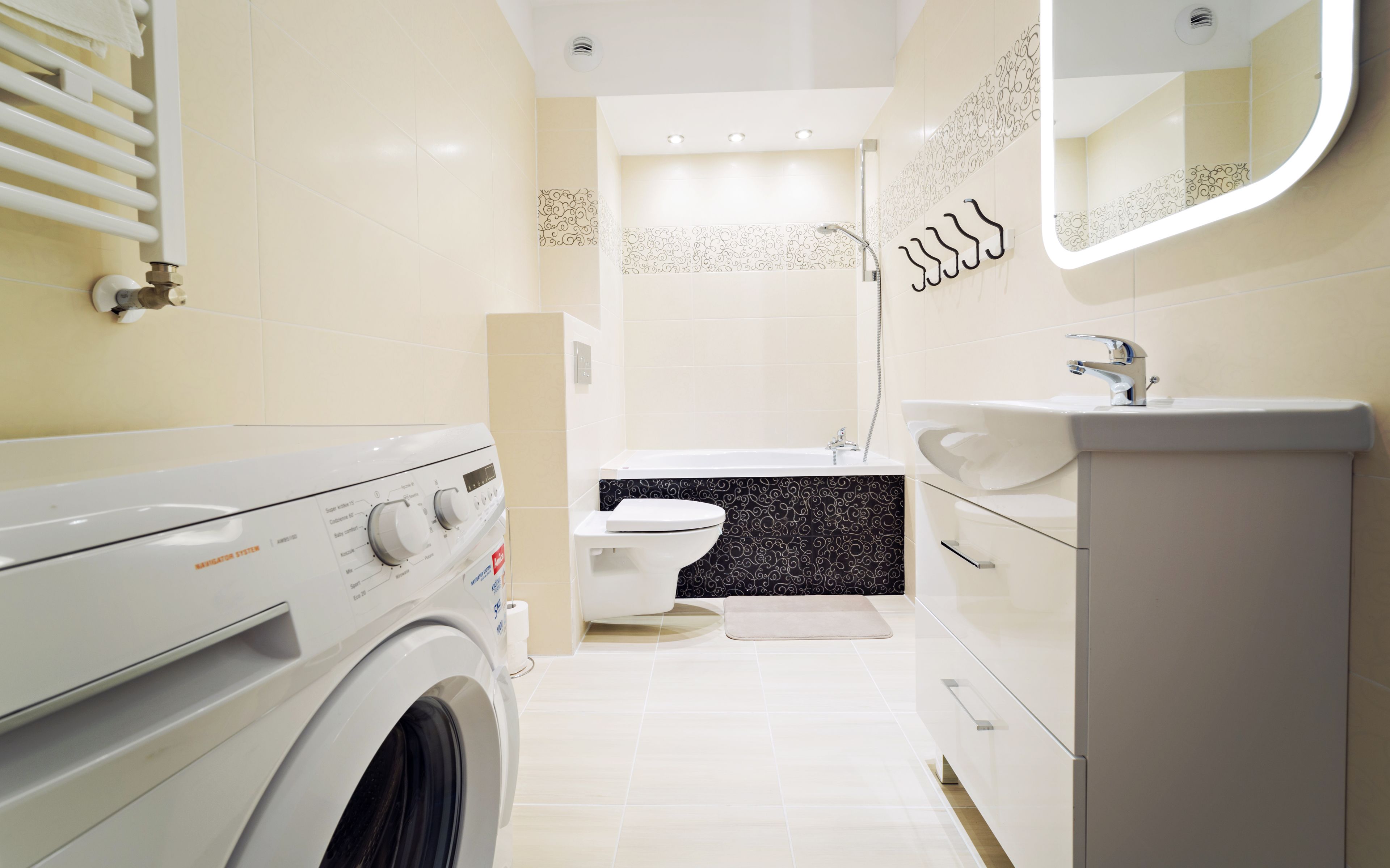 A modern bathroom with a washing machine, toilet, and sink.