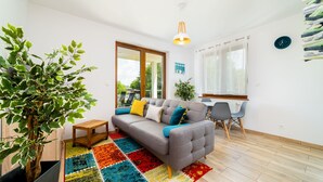 A modern living room with a grey sofa, colorful rug, wooden coffee table, and a potted plant.