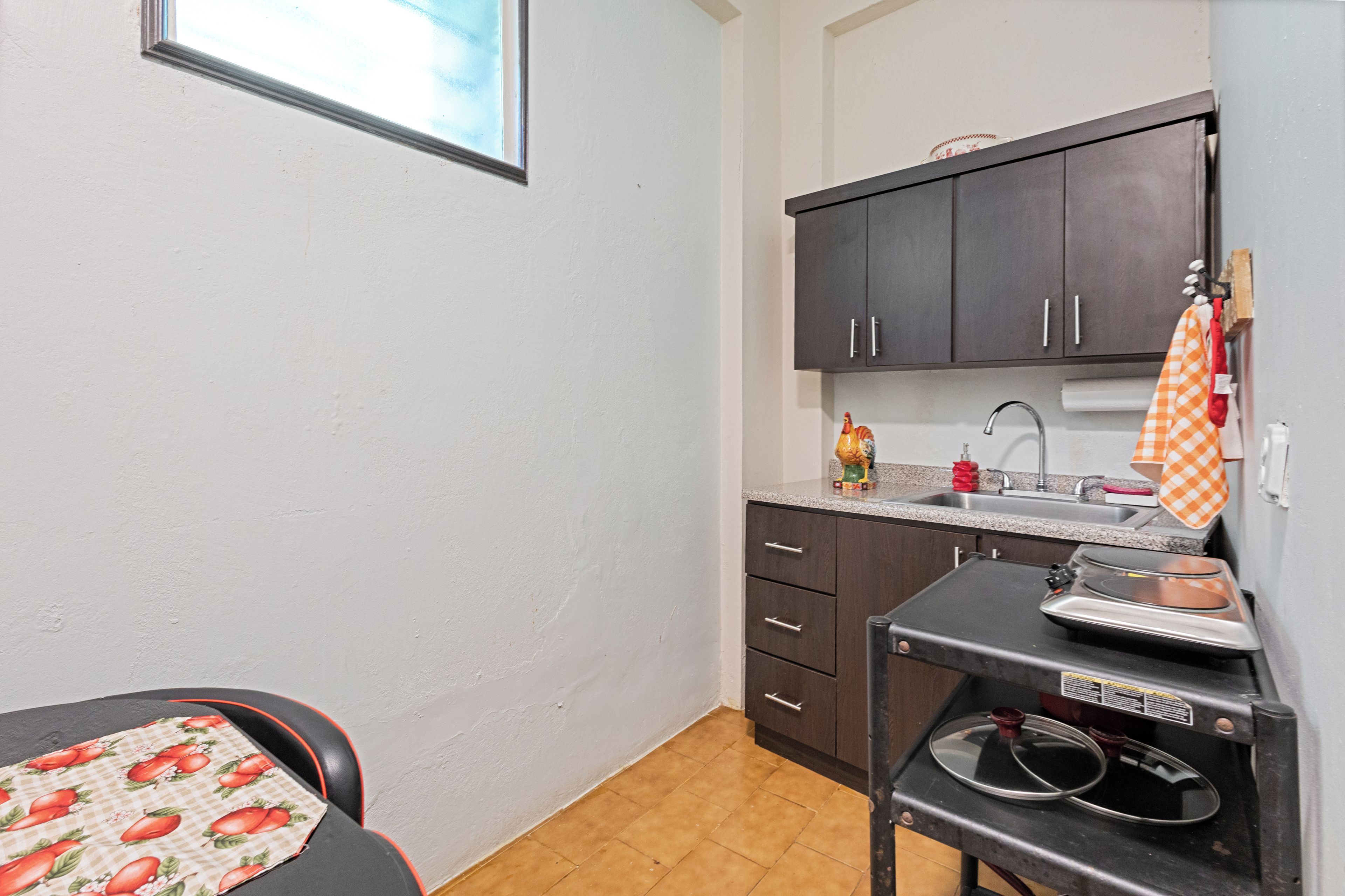 A compact kitchen with dark cabinets, a sink, and a small countertop.