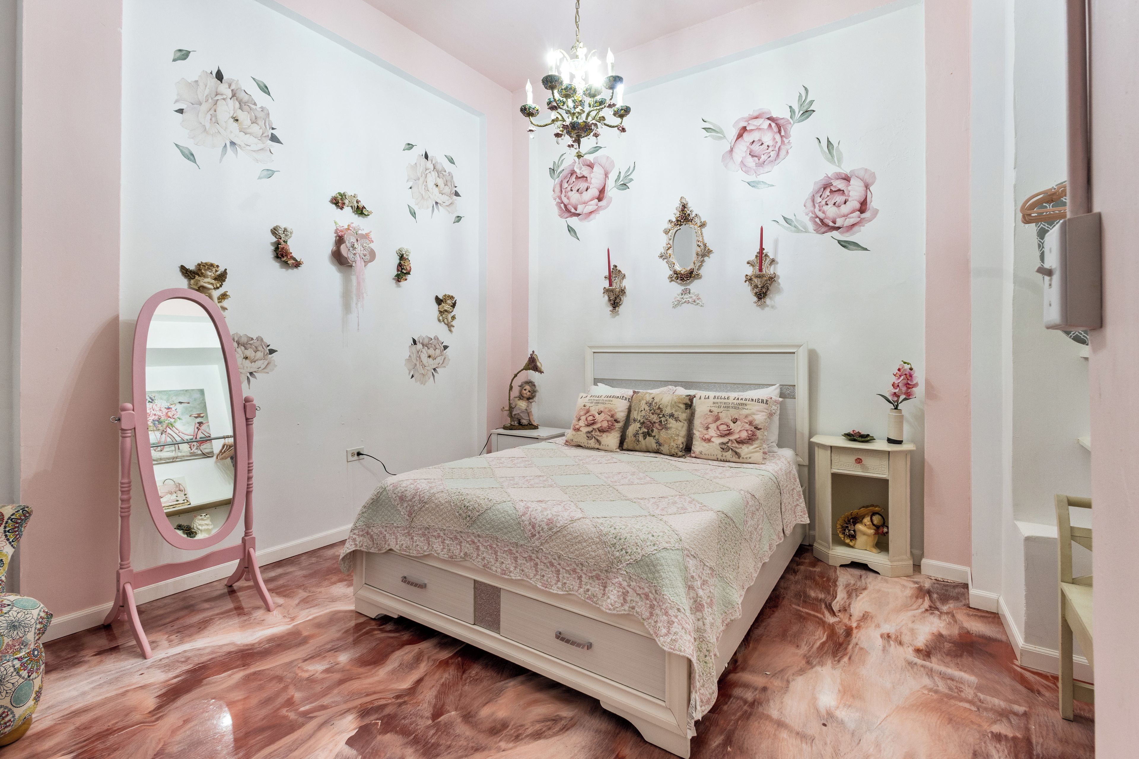 Un dormitorio con cama, cómoda, espejo y decoración en la pared.