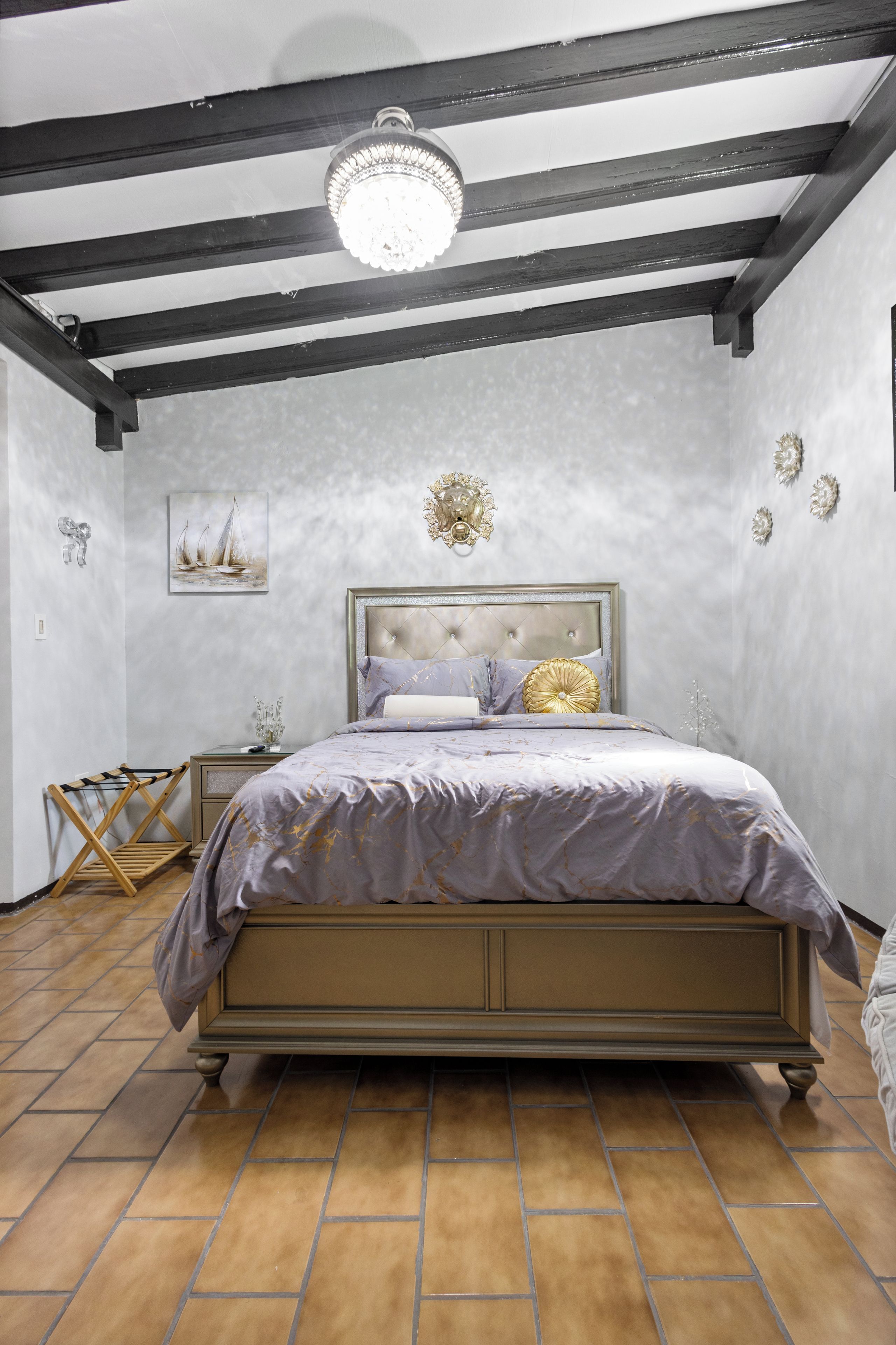 Un dormitorio con cama, mesita de noche, lámpara de pared y un adorno en la pared.