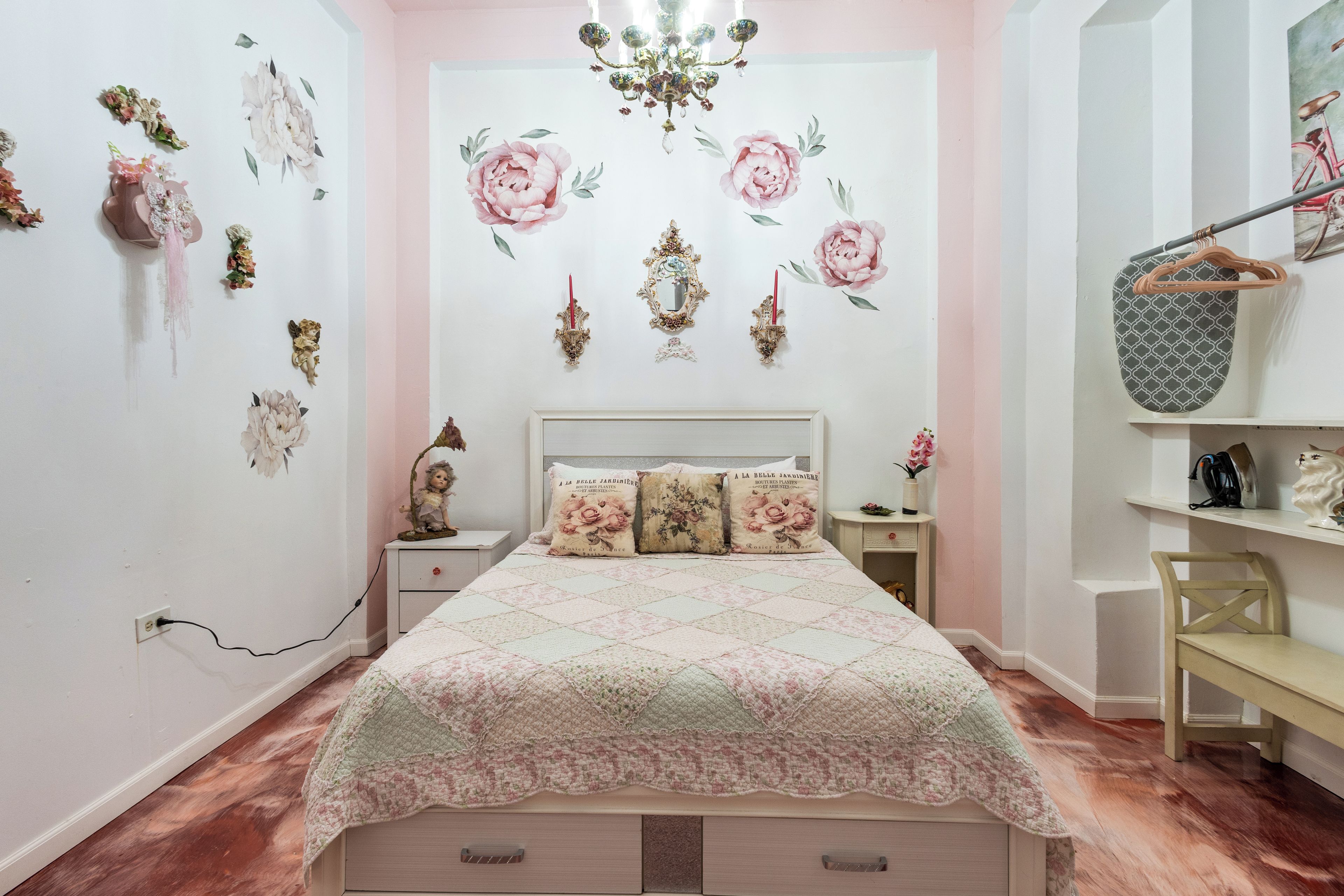 A bedroom with a bed, a nightstand, a dresser, a mirror, and a chandelier.
