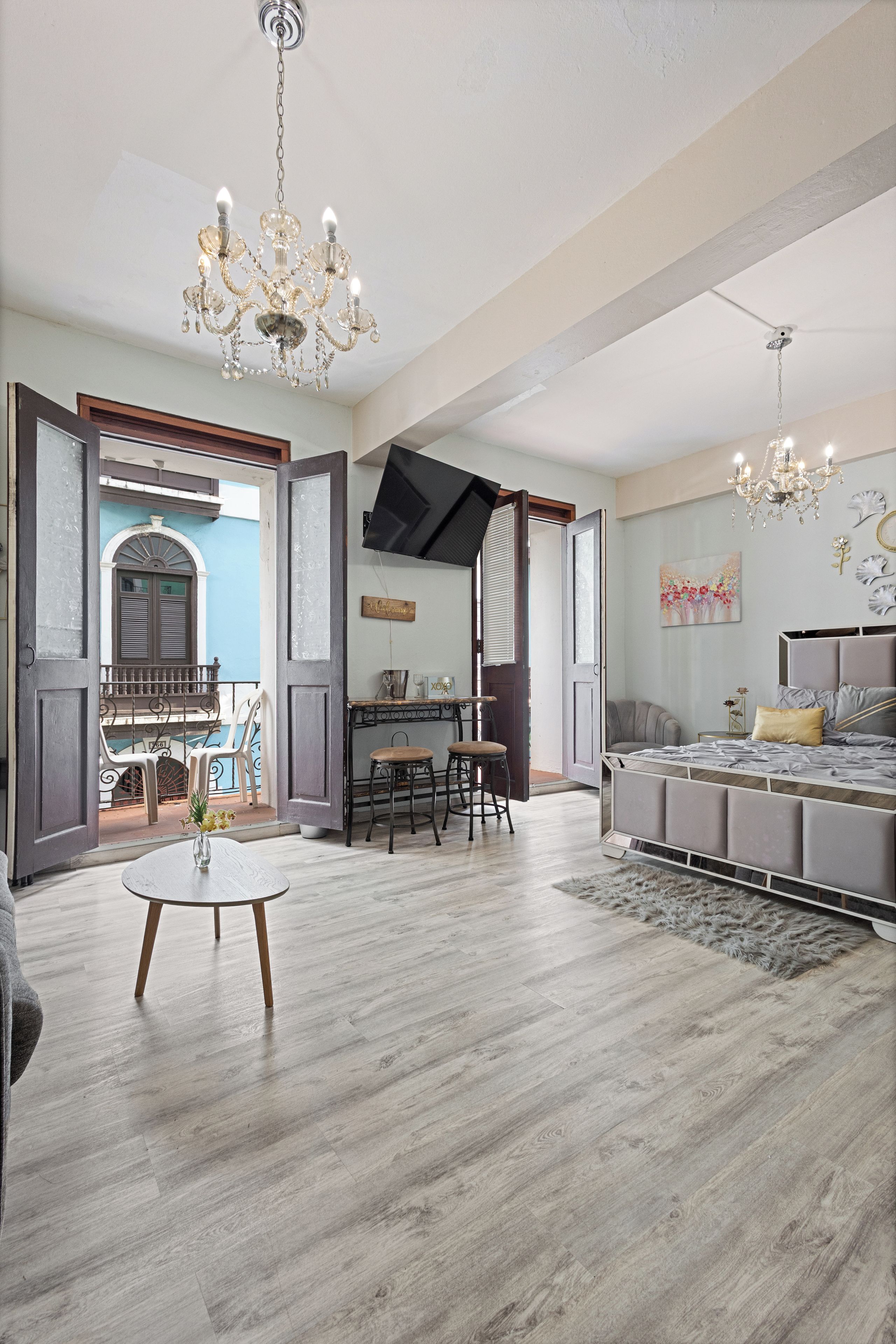 A spacious room with a dining area, a large bed, and a chandelier.