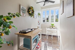 Eine Küche mit Holztisch, einer Waschmaschine, einem Deckenventilator und einem Fenster mit Blick auf Gebäude.