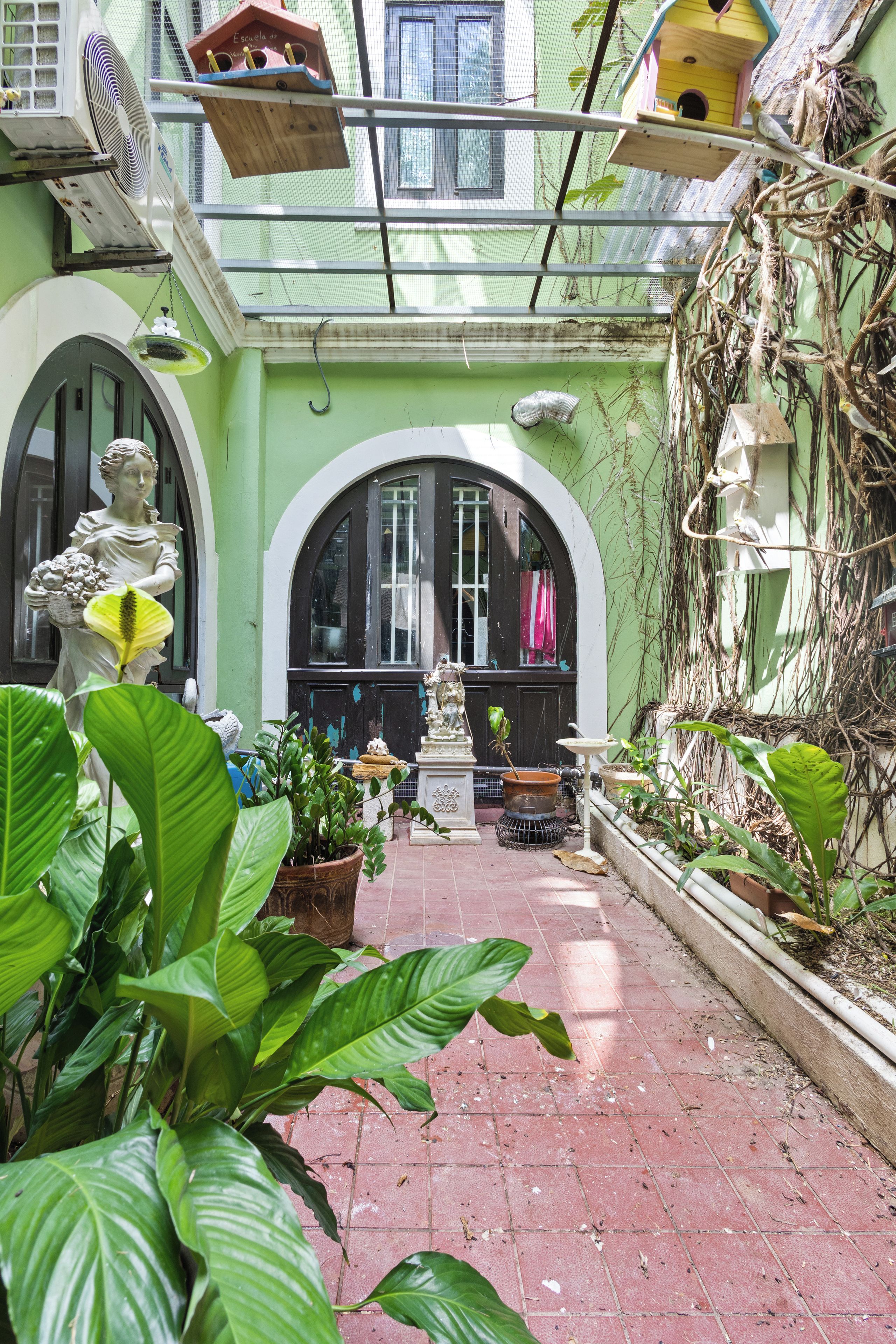 Un patio con una estatua, plantas en macetas y un comedero para pájaros.
