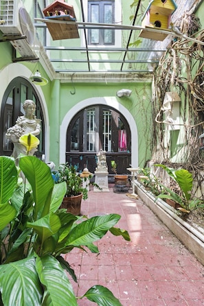 A courtyard with a statue, potted plants, and a birdhouse. - Casa Of Essence (San Juan)