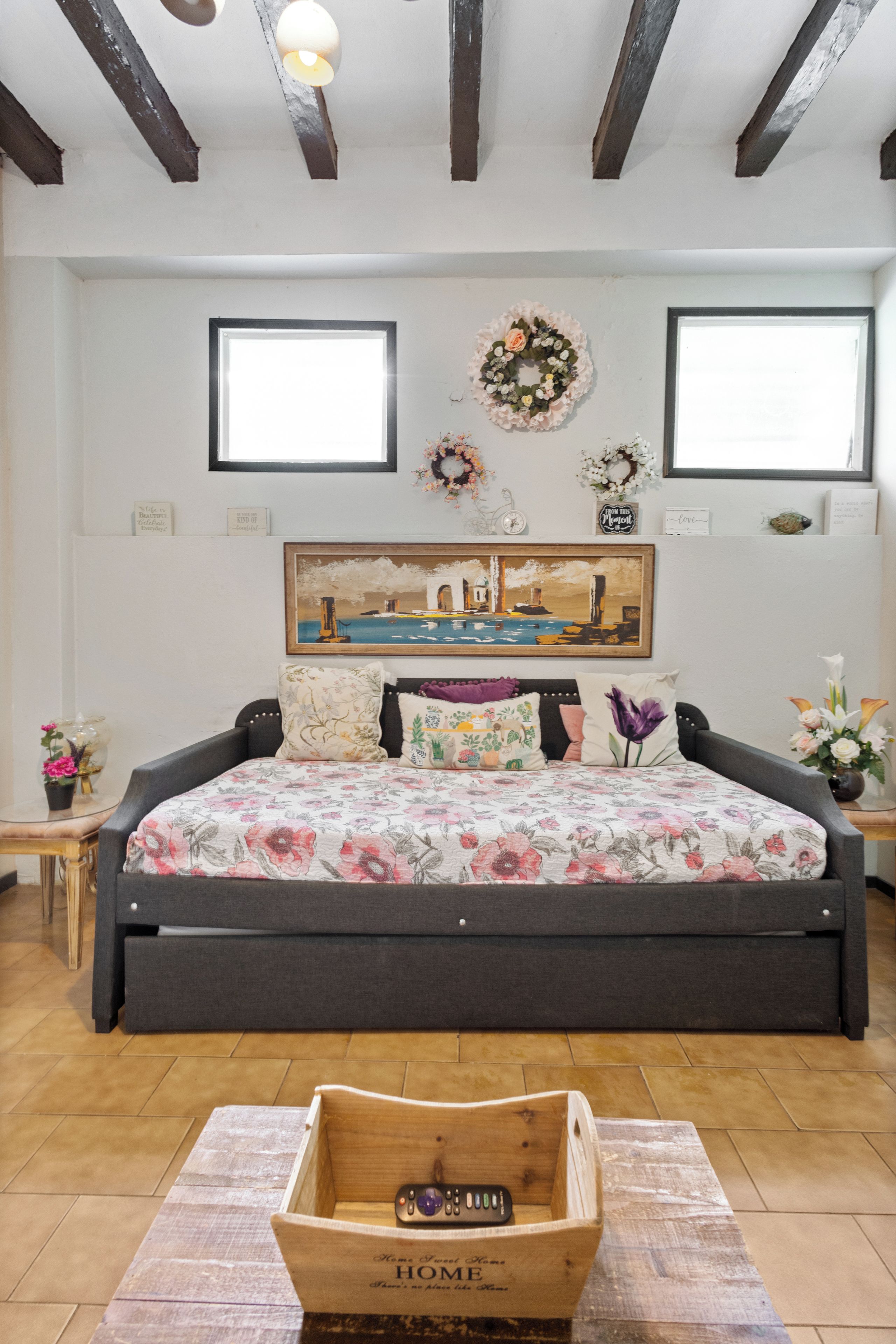 Un dormitorio con una cama grande, un cuadro sobre la cama y un cofre de madera en primer plano.