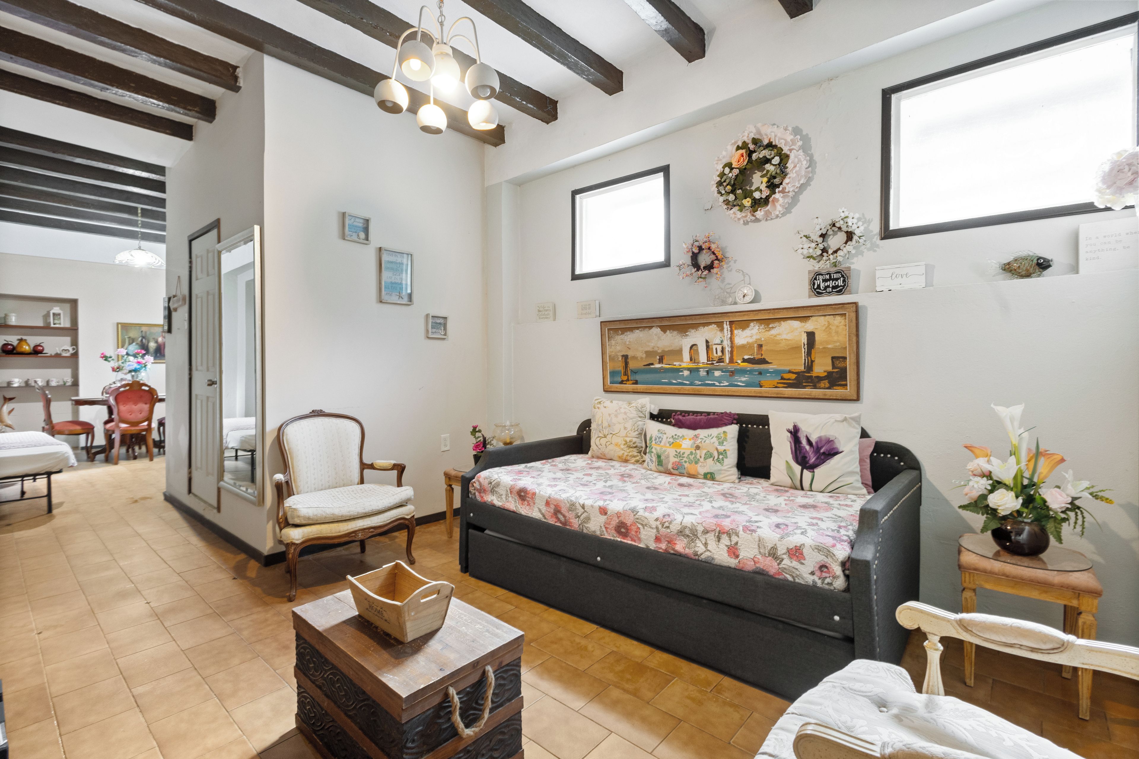 Una habitación con sofá, sillón, una mesita, cama y ventana.