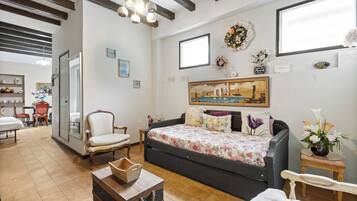 Una habitación con sofá, sillón, una mesita, cama y ventana.
