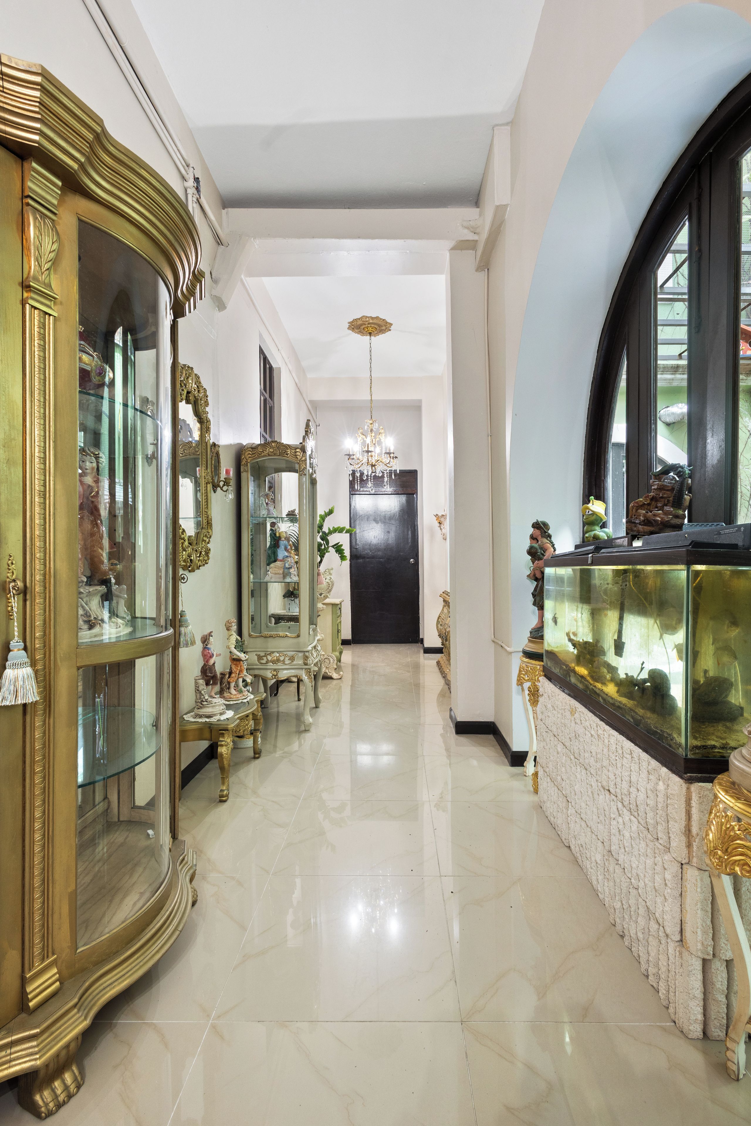 A hallway with ornate furniture, a fish tank, and a chandelier.