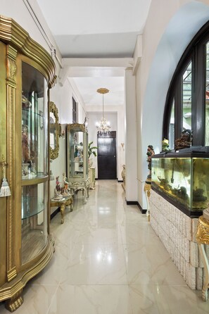 A hallway with ornate furniture, a fish tank, and a chandelier. - Casa Of Essence (San Juan)