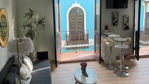 A modern living room with a sofa, a coffee table, and a balcony with a view of a building. - Casa Of Essence (San Juan)