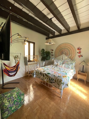 A bedroom with a bed, a hammock, a potted plant, a fan, and a lamp. - Casa Of Essence (San Juan)