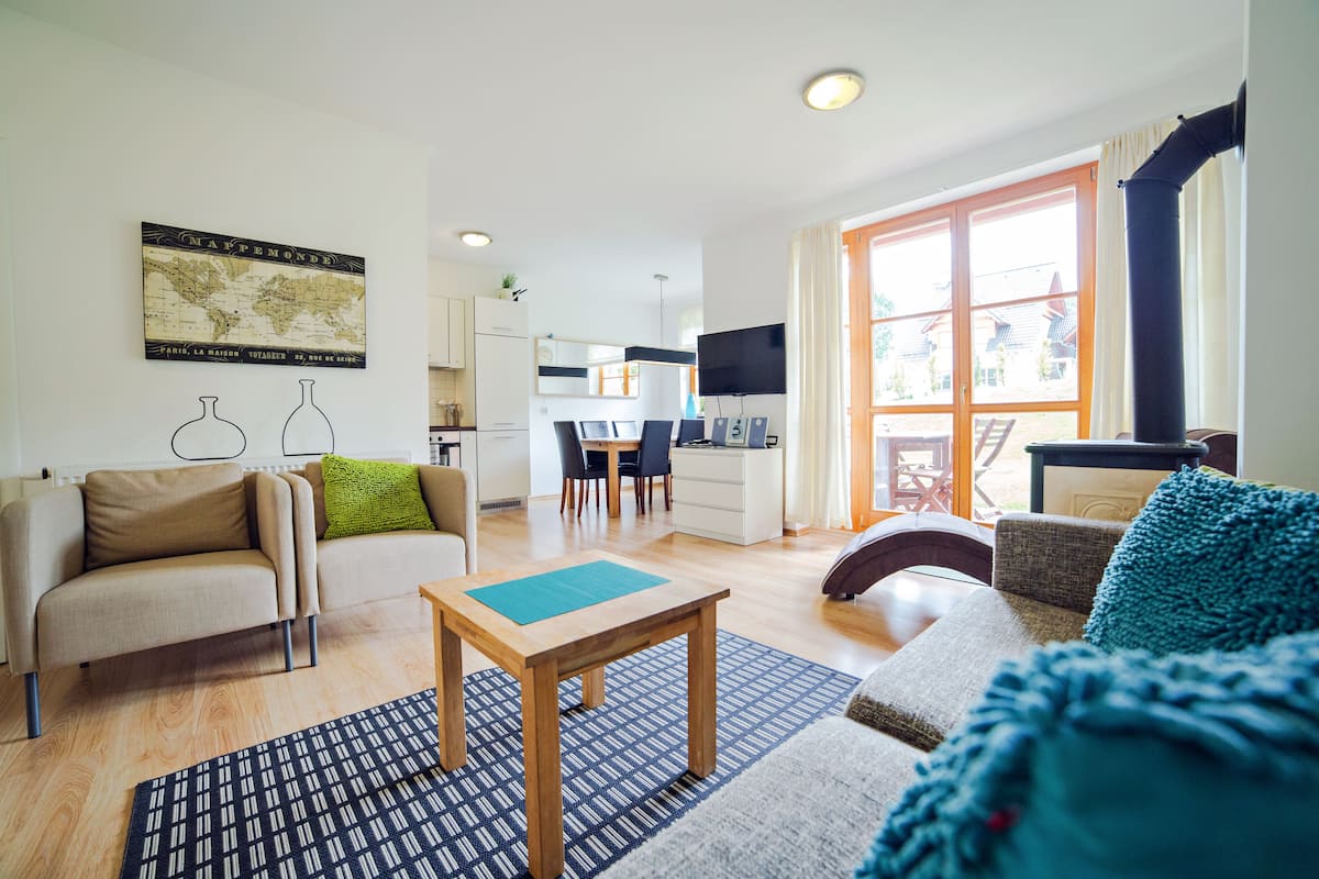 A modern living room with a sofa, a coffee table, and a dining area in the background.