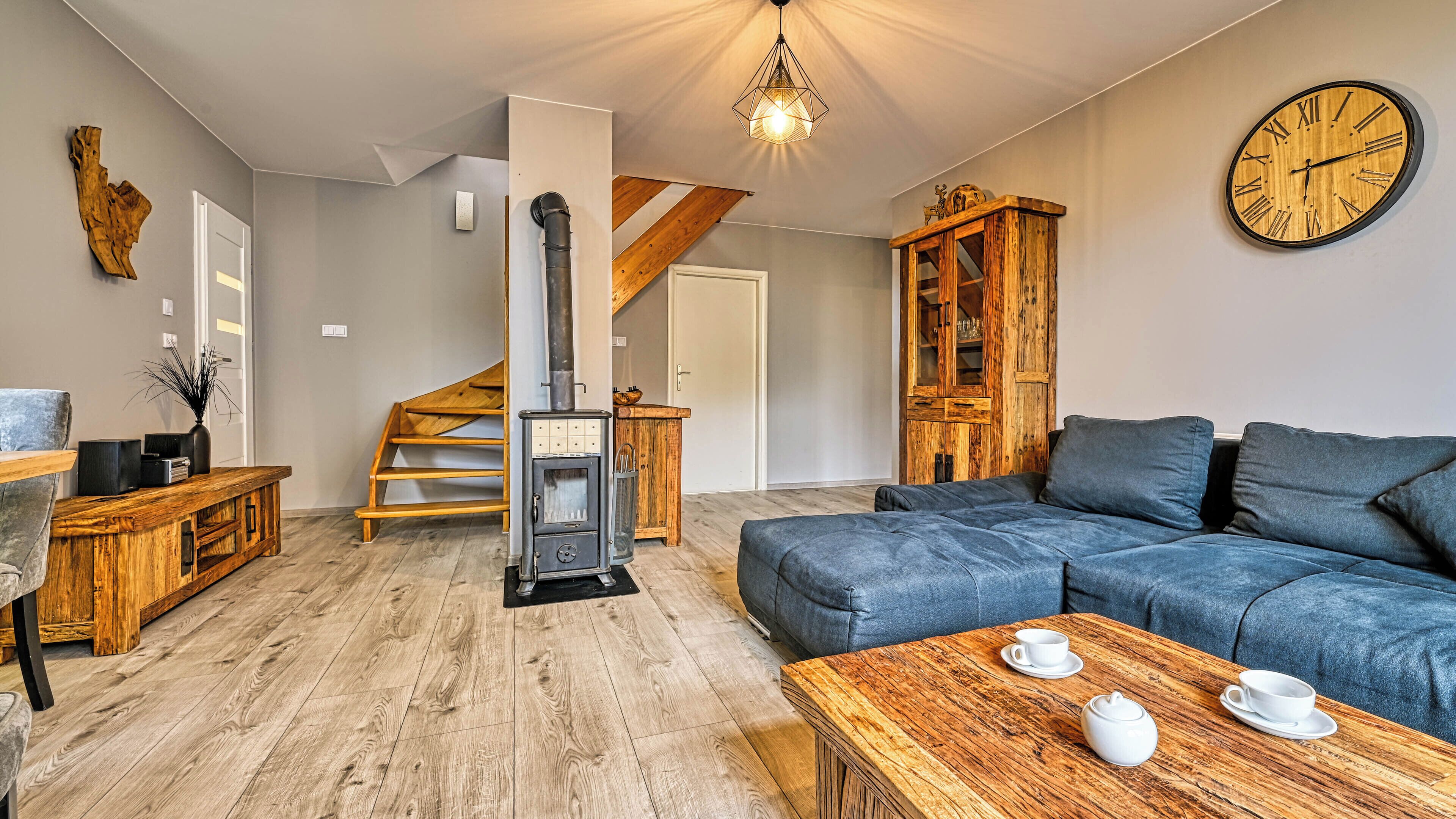 Una sala de estar acogedora con un sofá de madera, una mesa de centro con tazas, una chimenea y un mueble de madera.