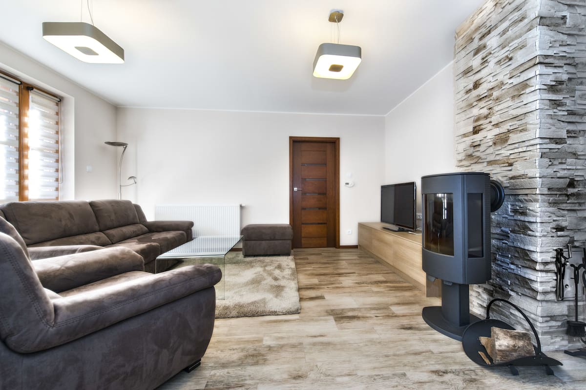 A modern living room with a sofa, a television, and a stone wall.