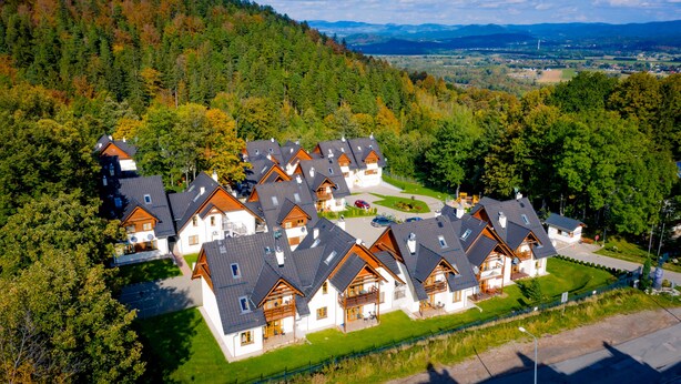A cluster of chalet-style houses with sloped roofs, wooden balconies, and a well-maintained lawn. - Apartamenty Sun & Snow Karpacz Myśliwska (Karpacz)