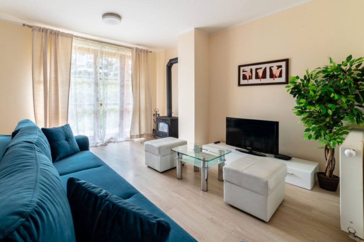 A modern living room with a sofa, a glass coffee table, a TV, and a fireplace.