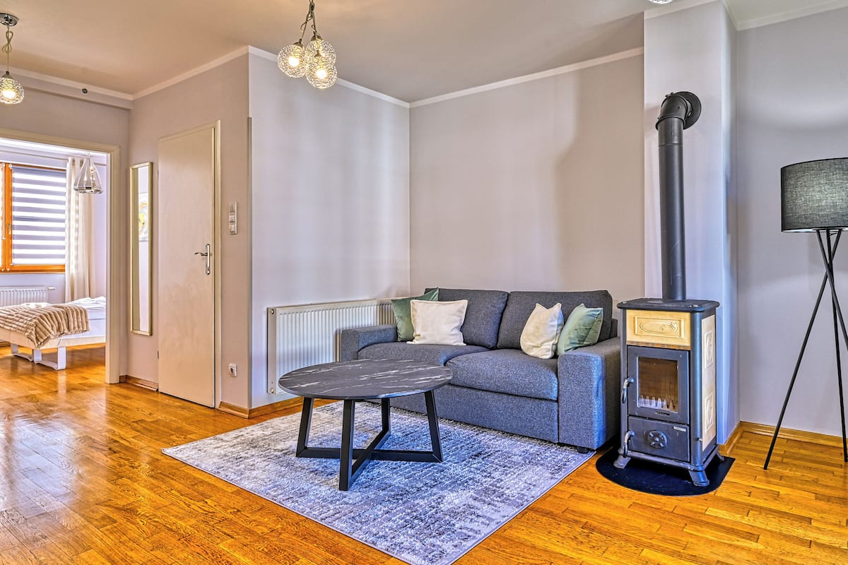A modern living room with a sofa, a small table, a standing heater, and a floor lamp.