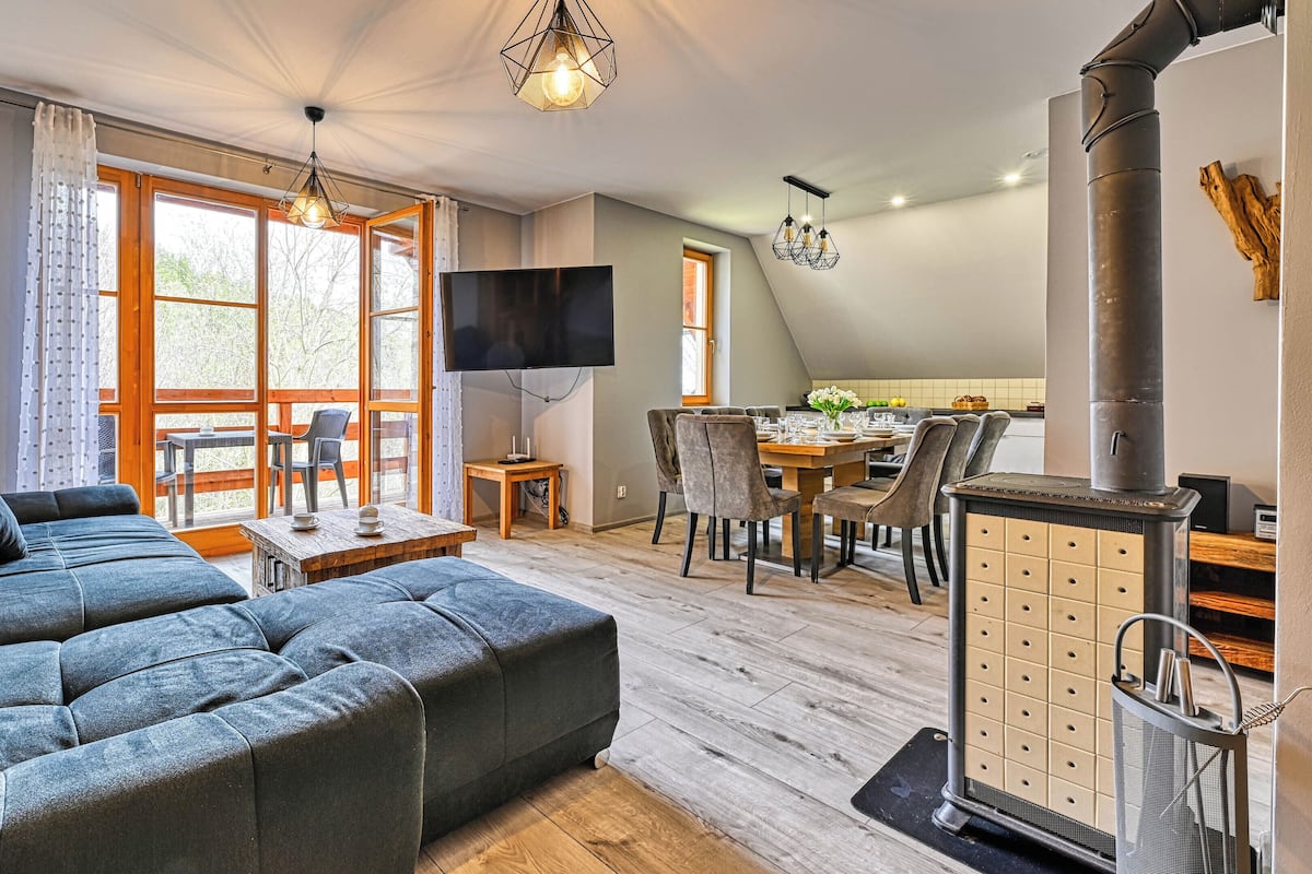 A modern living room with a sectional sofa, dining area with chairs, a TV, and a fireplace.