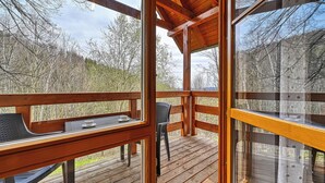 A wooden deck with a table and chairs, overlooking a forested area. - Apartamenty Sun & Snow Karpacz Myśliwska (Karpacz)