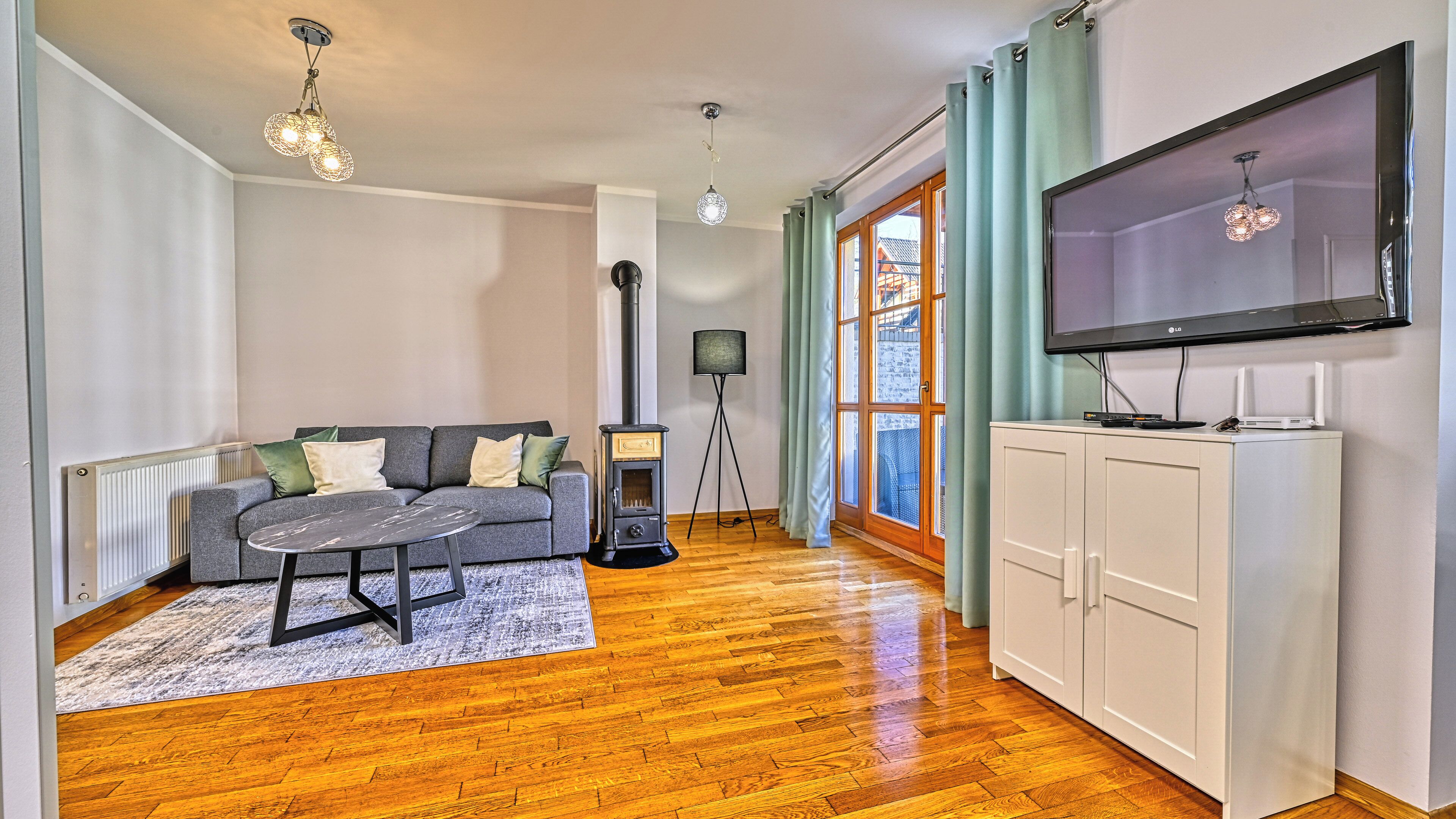 Un salon comprenant un canapé, une table basse, un téléviseur, une lampe sur pied et un radiateur.