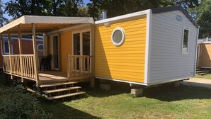 Una casa móvil amarilla y blanca con un porche y una pequeña terraza.