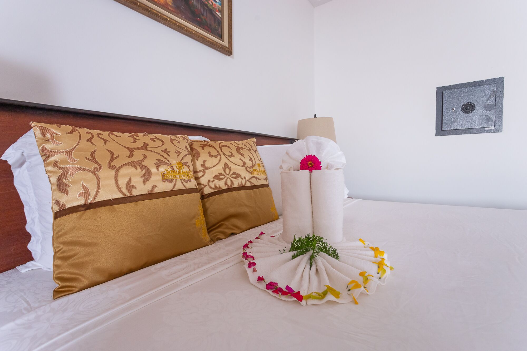 A neatly made bed with a decorative towel arrangement and a candle.