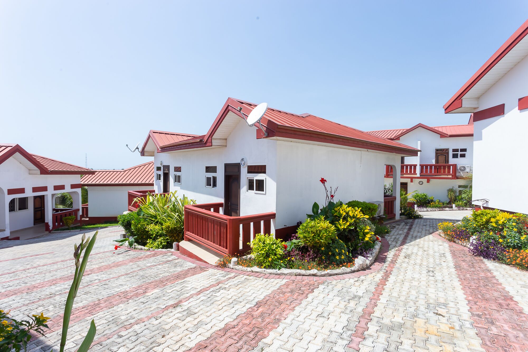 A row of white buildings with red roofs and a paved walkway.