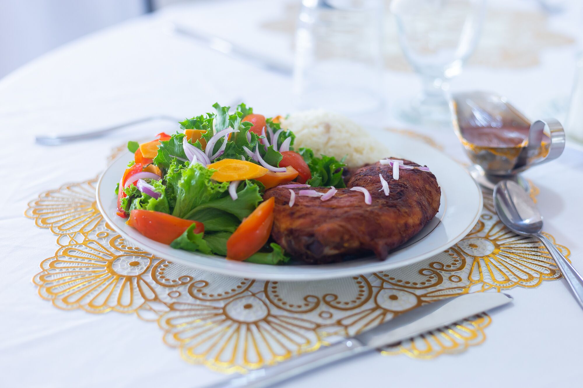 Un plato de comida con un guiso de carne, verduras y arroz sobre una mesa con un mantel decorativo.