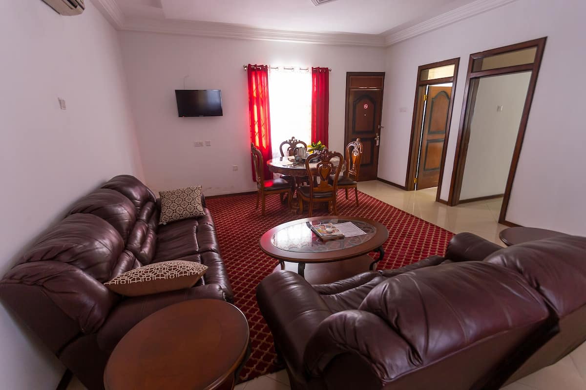 A living room with a leather sofa, a coffee table, and a dining area with a table and chairs.