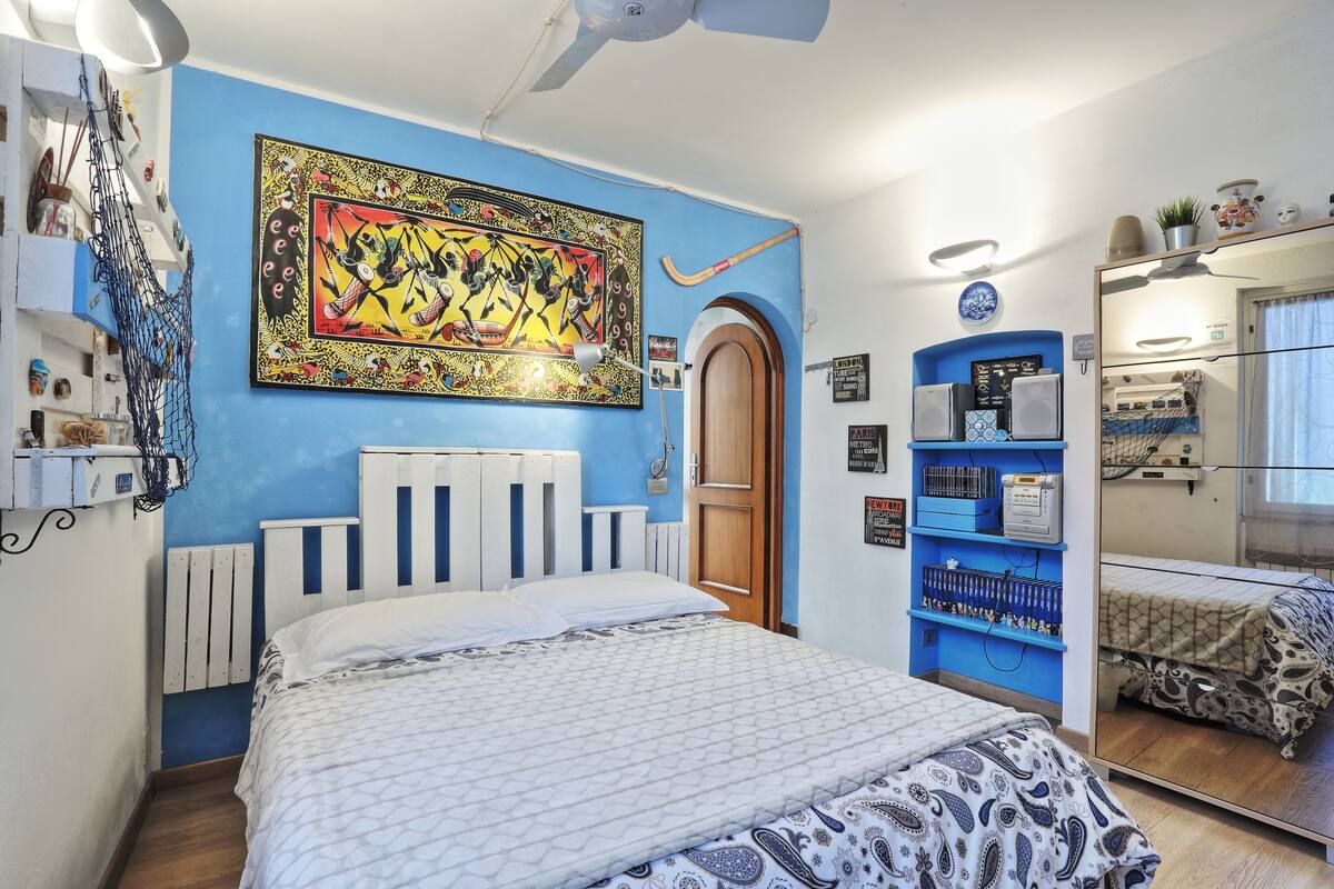 Une chambre à coucher avec un lit, un grand tableau, une armoire et un miroir.