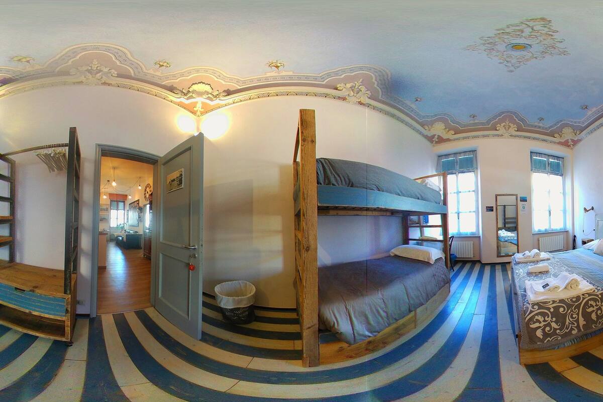 Une pièce avec des lits superposés, une chaise, une échelle et un sol circulaire à rayures.