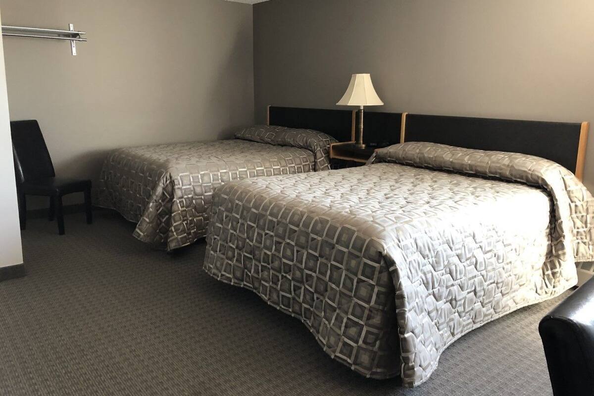 A hotel room with two beds, a desk, and a chair.