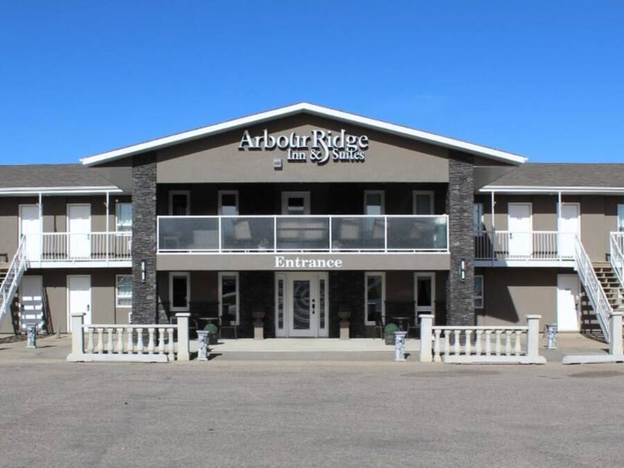 A two-story building with a sign reading "Arbour Ridge Inn & Suites" and an "Entrance" sign.