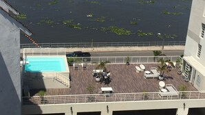 Ett poolområde på taket med utsikt över vattnet, solstolar och en liten trädgård.