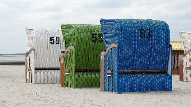 Sillas de playa con los números 59, 55 y 63 sobre arena.