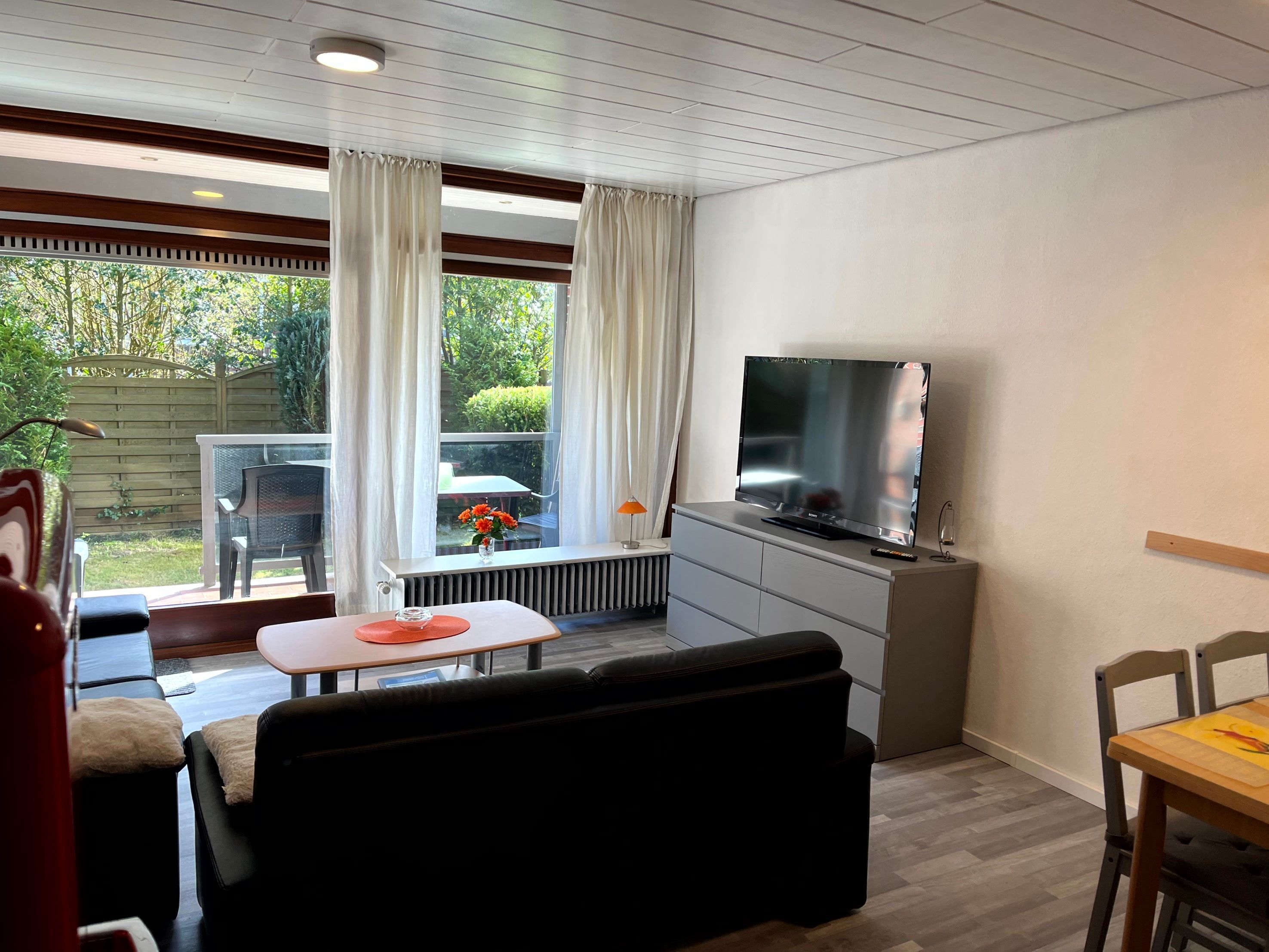 A living room with a TV, sofa, and dining table.