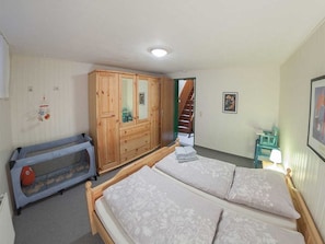 Ein Schlafzimmer mit einem Doppelbett, einem Holzschrank, einem kleinen Tisch und einem Babybett.