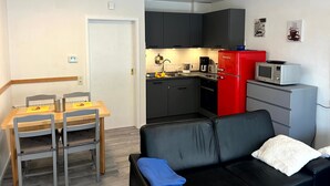 Un espacio habitable compacto con kitchenette, zona de comedor y área de estar.